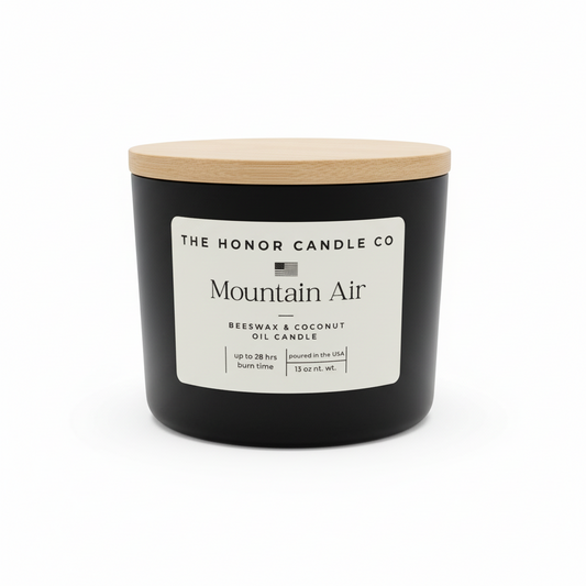 Black candle with wooden lid by The Honor Candle Co, featuring a label with text.